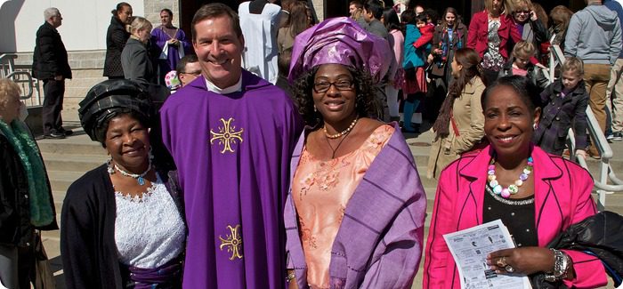 Priest smiling with three ladies next to him